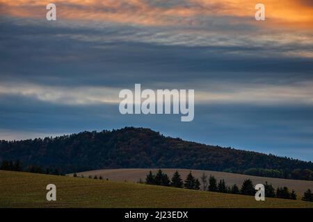 Cielo colorato con le nuvole sopra la collina al tramonto. Foto Stock