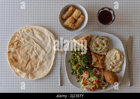 Vista dall'alto di un piatto di specialità libanesi, pane pita e una ciotola di dolci Foto Stock