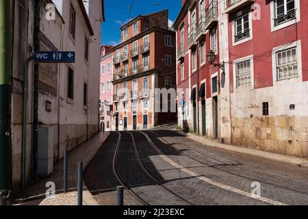 Strada stretta a Lisbona Portogallo con tram piste pubbliche servizi igienici sul lato. Foto Stock