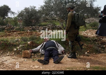 Un anziano palestinese che si è adagiato a terra dopo essere stato assalito da un soldato israeliano nella città di Qasra, vicino all'insediamento israeliano di Migdalim nella Cisgiordania occupata. I soldati israeliani si scontrano con i cittadini di Qasra dopo aver organizzato una manifestazione in occasione della Giornata della Terra contro il sequestro delle loro terre, il taglio degli olivi e l'espansione degli avamposti, La mano delle forze israeliane durante le proteste di massa del 1976 e contro i piani di espropriazione della terra in Galilea. (Foto di Nasser Ishtayeh/SOPA Images/Sipa USA) Foto Stock