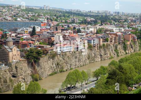 Foto aerea di Tbilisi, Georgia. Vecchie case e ristoranti sono su una costa rocciosa del fiume Kura in una giornata estiva soleggiata Foto Stock