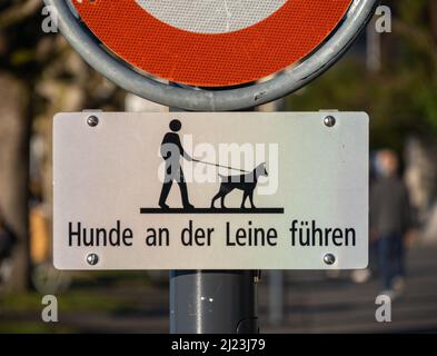 Zug, Svizzera - 31 dicembre 2021: Segnale di avvertimento prima del percorso per passeggini lungo il lago di Zug, il testo sta dicendo tenere il cane sul guinzaglio Foto Stock