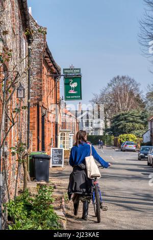 Un ciclista in High Street, Castello Acre, Norfolk. Foto Stock