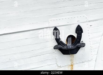 Primo piano di un ancoraggio nero sul lato della nave dipinto di bianco. Foto Stock