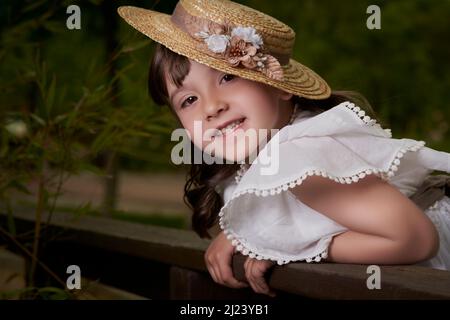 Ragazza di comunione in posa appoggiata contro una recinzione di legno nel parco Foto Stock