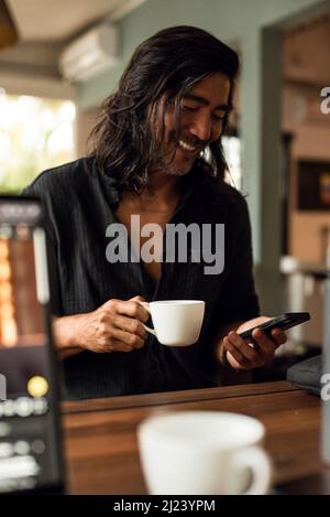 Uomo bere caffè e leggere notizie sul cellulare Foto Stock