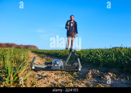 scioccato uomo con drone rotto. Uomo preoccupato con gadget crash. Giovane eccitato (uomo deluso) con drone che cade sul campo. Selezione f Foto Stock