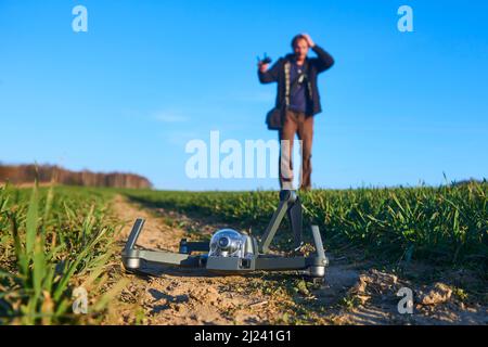 scioccato uomo con drone rotto. Uomo preoccupato con gadget crash. Giovane eccitato (uomo deluso) con drone che cade sul campo. Selezione f Foto Stock