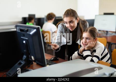 L'insegnante insieme agli studenti conduce una lezione sull'educazione informatica Foto Stock