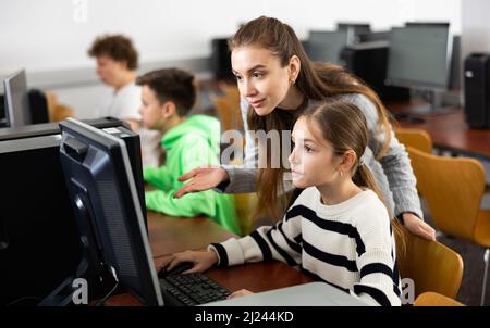 L'insegnante insieme agli studenti conduce una lezione sull'educazione informatica Foto Stock