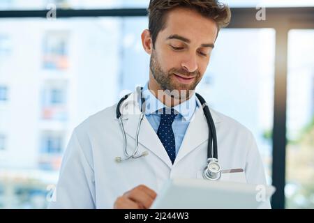 Ottenere una seconda opinione online. Shot di un medico impegnato che controlla le cartelle cliniche di un paziente sulla sua tavoletta. Foto Stock