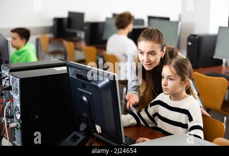 L'insegnante insieme agli studenti conduce una lezione sull'educazione informatica Foto Stock