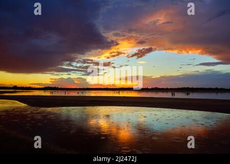 La fine di una calda giornata di Summers nell'estremo nord occidentale Victoria, con gocce di pioggia che cadono in un lago salino, con il tramonto drammatico che forma lo sfondo. Foto Stock