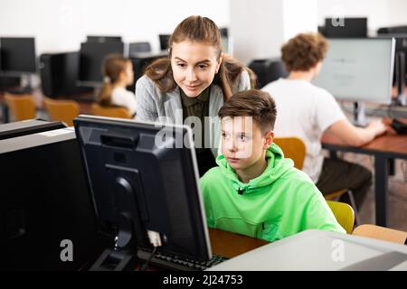 L'insegnante insieme agli studenti conduce una lezione sull'educazione informatica Foto Stock