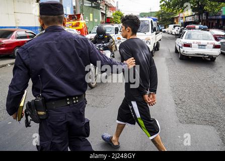 San Salvador, El Salvador. 29th Mar 2022. La polizia scorta un presunto membro della banda in un centro di detenzione. Il Congresso Salvadoran ha approvato uno Stato di emergenza la Domenica 27th dopo che il paese ha registrato i suoi casi di violenza più alta nella storia recente con 62 omicidi a causa di violenza legata a gang.secondo il governo Salvadoran più di 1.400 presunti membri di gang dalla MS-13 e Barrio 18 gang sono stati catturato. Credit: SOPA Images Limited/Alamy Live News Foto Stock