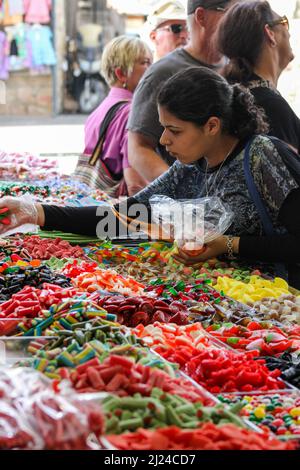 Una donna seleziona le caramelle colorate da un venditore di mercato a Gerusalemme, Israele. Foto Stock