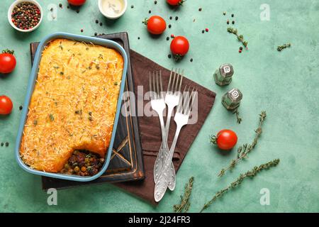 Piatto da forno con gustosa torta Shepherd su sfondo verde Foto Stock