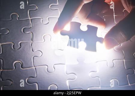 Tutto insieme. Colpo concettuale di una mano di persone che costruisce un puzzle. Foto Stock