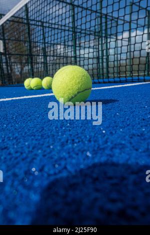 fuoco selettivo, palle da paddle tennis di fronte alla rete di un campo da paddle tennis blu Foto Stock