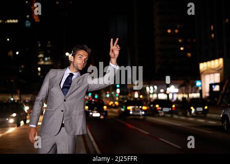 Taxi. Un bel uomo d'affari che si accane un taxi mentre si trova in una strada trafficata di notte. Foto Stock