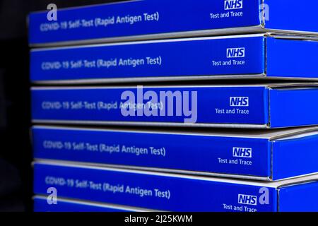 Scatole kit per test a flusso laterale NHS Covid-19 blu / kit per test per coronavrus con antigene a flusso laterale rapido su sfondo nero Foto Stock