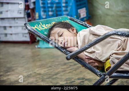 Bangkok, Thailandia - 12 maggio 2009: La giovane ragazza non identificata dorme nel negozio del mercato dei fiori Pak Klong Thalat prima mattina. Foto Stock