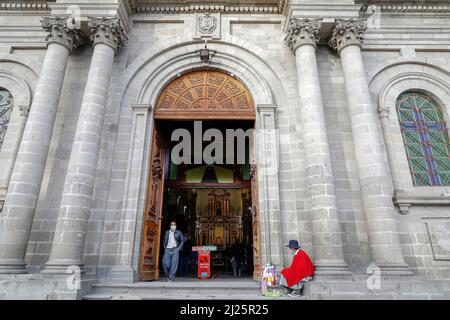 L'uomo indigeno vende cose fuori dalla chiesa di San Antonio a Riobamba, Ecuador Foto Stock
