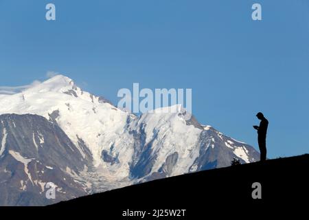Massiccio del Monte Bianco in estate. Silhouette di uomo che legge la bibbia in natura. Meditazione. Foto Stock