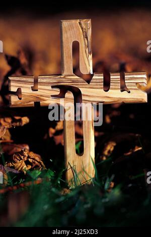Croce cristiana su foglie d'autunno secche cadute. Fede e spiritualità. Foto Stock