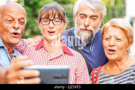 Coppie anziane che prendono selfie con smartphone - riunione degli amici anziani divertirsi all'aperto con gli altri Foto Stock