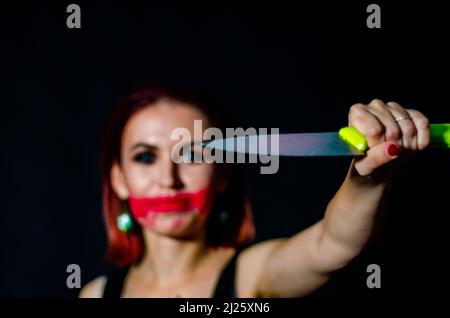 Splendida donna rossa con coltello sanguinoso in mano primo piano Foto Stock