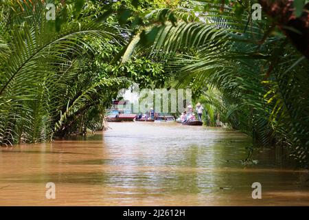 Sampans su un canale di mare appartato sotto le palme nipa sovrastanti nel Delta del Mekong, Tân an Thượng, Tân Thạch, Châu Thành, Bến tre, Vietnam Foto Stock
