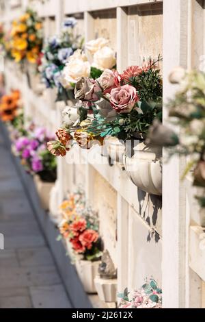 Cimitero murale italiano con lapidi e fiori artificiali in una soleggiata giornata estiva a Venezia, Isola di San Michele. Commemorazione dei morti, Foto Stock