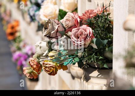 Cimitero murale italiano con lapidi e fiori artificiali in una soleggiata giornata estiva a Venezia, Isola di San Michele. Commemorazione dei morti, Foto Stock