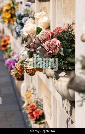 Cimitero murale italiano con lapidi e fiori artificiali in una soleggiata giornata estiva a Venezia, Isola di San Michele. Commemorazione dei morti, Foto Stock