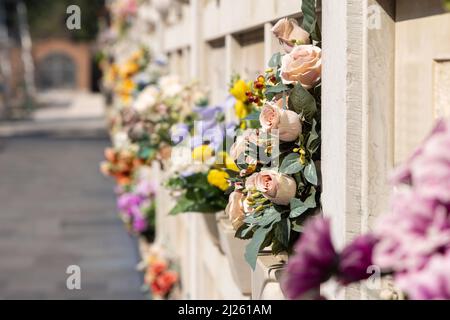 Cimitero murale italiano con lapidi e fiori artificiali in una soleggiata giornata estiva a Venezia, Isola di San Michele. Commemorazione dei morti, Foto Stock