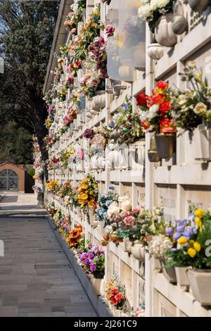 Cimitero murale italiano con lapidi e fiori artificiali in una soleggiata giornata estiva a Venezia, Isola di San Michele. Commemorazione dei morti, Foto Stock