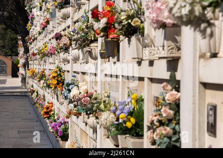 Cimitero murale italiano con lapidi e fiori artificiali in una soleggiata giornata estiva a Venezia, Isola di San Michele. Commemorazione dei morti, Foto Stock