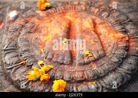 Mandala. Buddha dipinto di rosso con due piedi e fiori offerti. Foto Stock