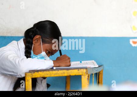 Scuola secondaria. Ragazza che indossa una maschera chirurgica in classe. Foto Stock