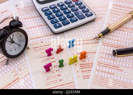 Società fiscale. Testo 'tax time' sulla dichiarazione australiana con orologio e calcolatore in primo piano Foto Stock