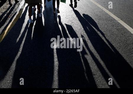 Sagome nere e ombre delle persone per strada. Folla che cammina sul marciapiede, concetto di pedoni, crimine, società, vita cittadina. Foto Stock