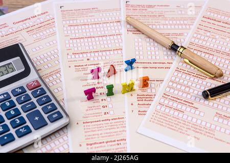 Società fiscale. Testo 'tax time' sulla dichiarazione australiana con orologio e calcolatore in primo piano Foto Stock