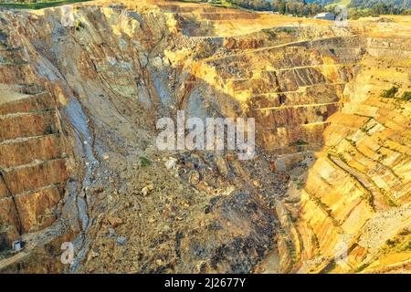 Vista su una miniera d'oro a cielo aperto, con terrazze per il trasporto di minerali. Un scivolo ha crollato un muro della buca. Martha Mine, Waihi, Nuova Zelanda Foto Stock