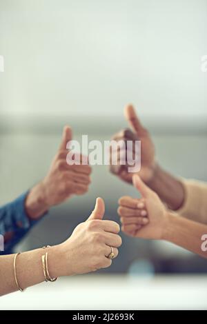 Stai facendo molto bene. Primo piano di un gruppo di uomini d'affari che danno i pollici insieme. Foto Stock