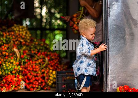 Un ragazzo albino afro-colombiano è appeso durante la lavorazione della frutta condaduro (palma di pesca) in una struttura a Cali, Valle del Cauca, Colombia. Foto Stock