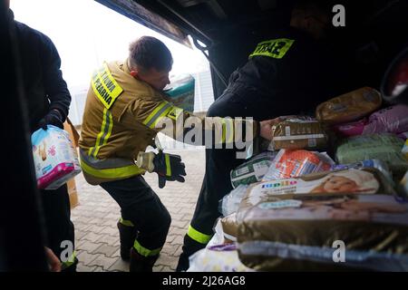 Una guardia carica le forniture di aiuti su un autobus di proprietà del volontario britannico Cliff Wilson che la trasporterà da Przemysl in Polonia all'Ucraina e, al suo ritorno, raccoglierà donne e bambini ucraini e li riporterà attraverso il confine per la sicurezza in Polonia. Data foto: Mercoledì 30 marzo 2022. Foto Stock