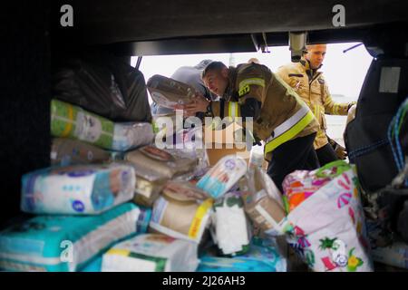 Una guardia carica le forniture di aiuti su un autobus di proprietà del volontario britannico Cliff Wilson che la trasporterà da Przemysl in Polonia all'Ucraina e, al suo ritorno, raccoglierà donne e bambini ucraini e li riporterà attraverso il confine per la sicurezza in Polonia. Data foto: Mercoledì 30 marzo 2022. Foto Stock