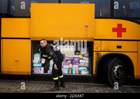 Una guardia carica le forniture di aiuti su un autobus di proprietà del volontario britannico Cliff Wilson che la trasporterà da Przemysl in Polonia all'Ucraina e, al suo ritorno, raccoglierà donne e bambini ucraini e li riporterà attraverso il confine per la sicurezza in Polonia. Data foto: Mercoledì 30 marzo 2022. Foto Stock