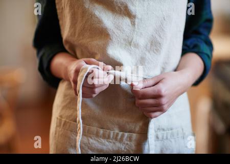 Preparazione. Una giovane donna che indossa un grembiule. Foto Stock